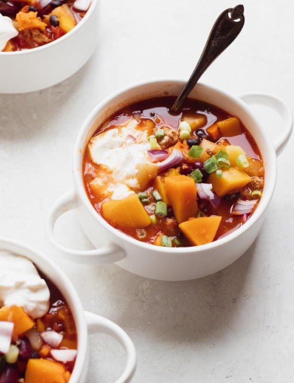 chili in a white soup bowl topped with green onions and sour cream