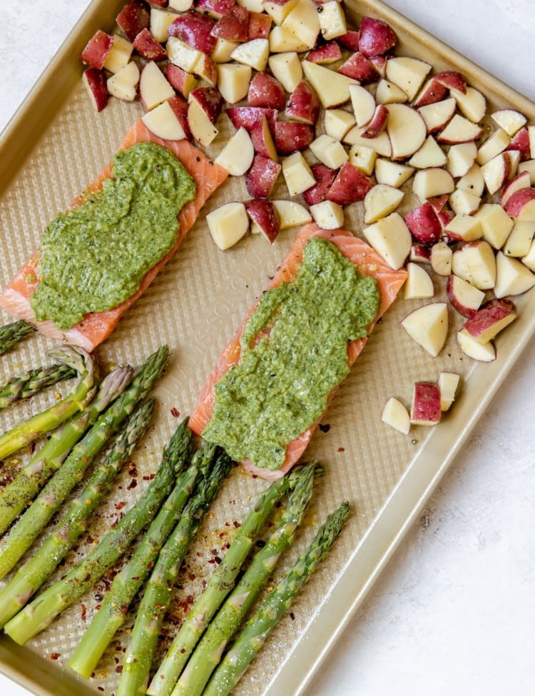 salmon with veggies on a gold sheet pan