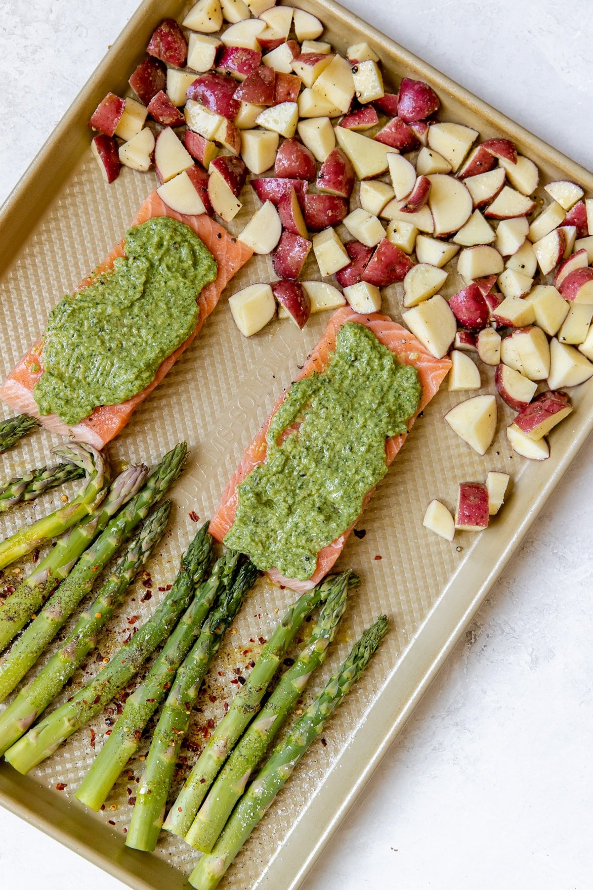 salmon with veggies on a gold sheet pan