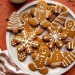 snowflake, tree, candy cane, and gingerbread men cookies with white icing on a white circle plate