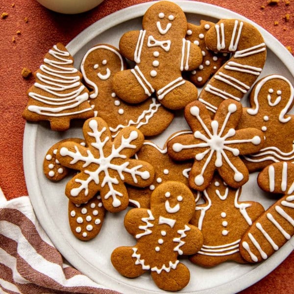 snowflake, tree, candy cane, and gingerbread men cookies with white icing on a white circle plate