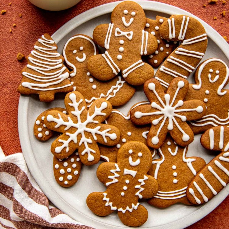 snowflake, tree, candy cane, and gingerbread men cookies with white icing on a white circle plate
