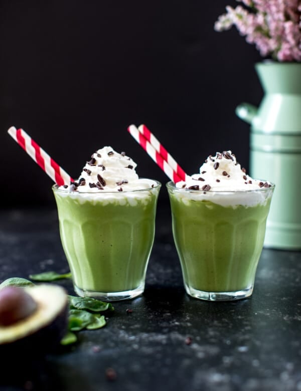 a green smoothie in a glass cup topped with whipped cream
