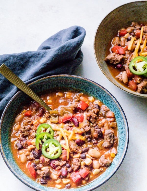 Lamb Chili in a bowl topped with jalapenos with a grey napkin on the side