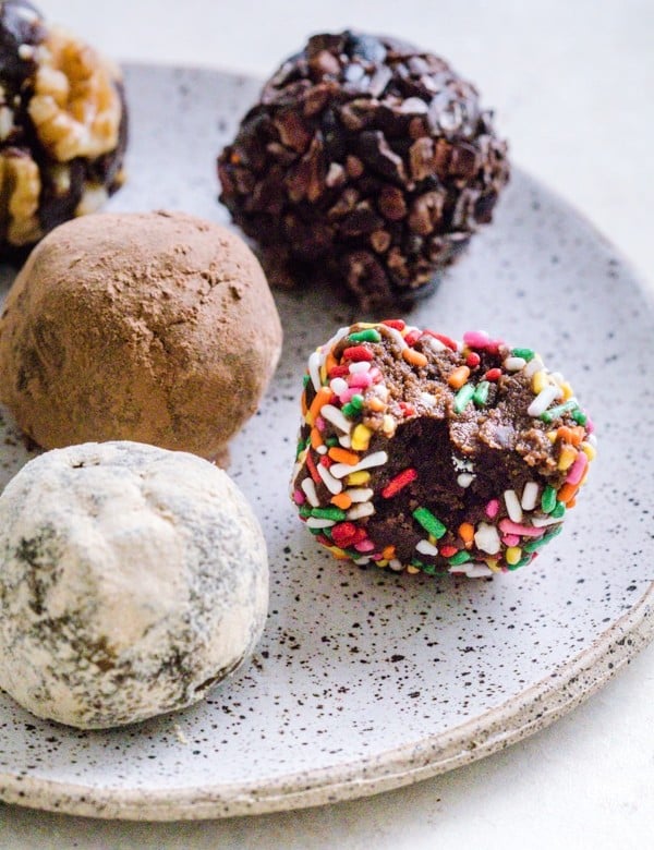 Chocolate Brownie Bites on a plate covered in different toppings like sprinkles and cocoa powder.