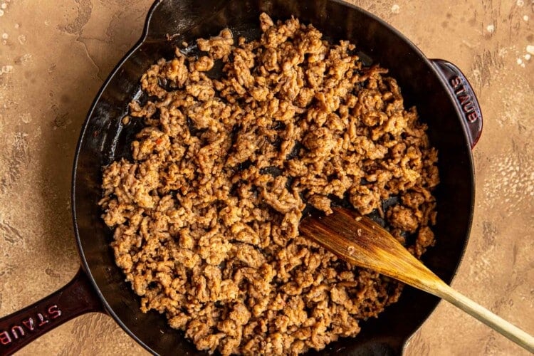ground meat with wooden spoon in black cast iron skillet