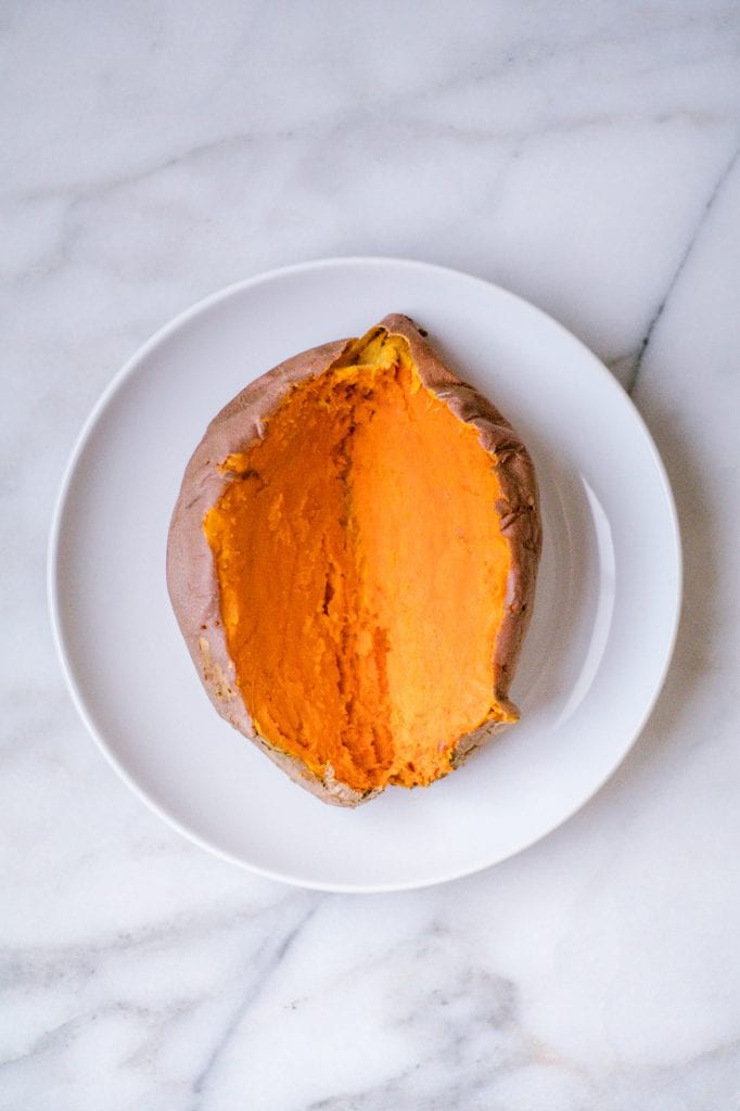Sweet potato cooked and cut in half on a marble board.