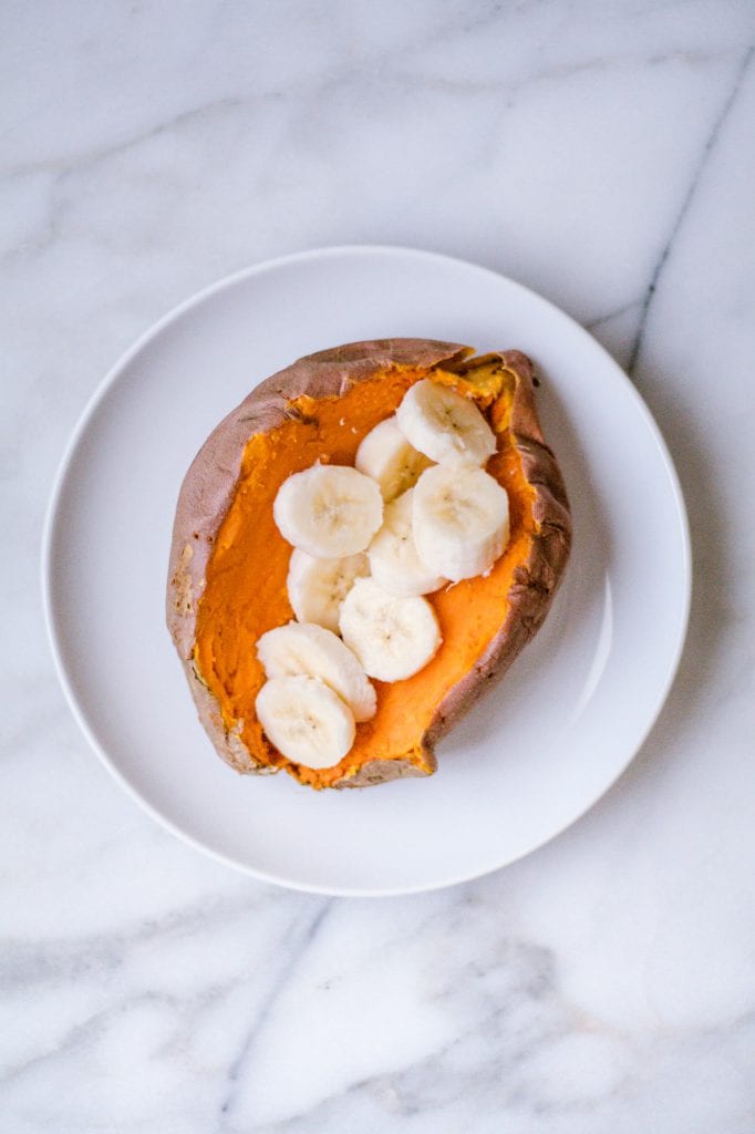 Cooked sweet potato cut in half with a banana sliced and placed on top.