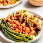 chicken on a white plate with veggies, cranberries and apricots