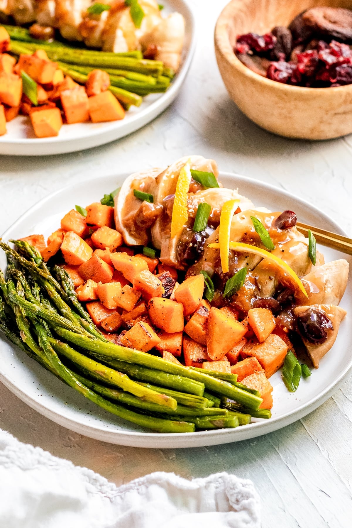 chicken on a white plate with veggies, cranberries and apricots