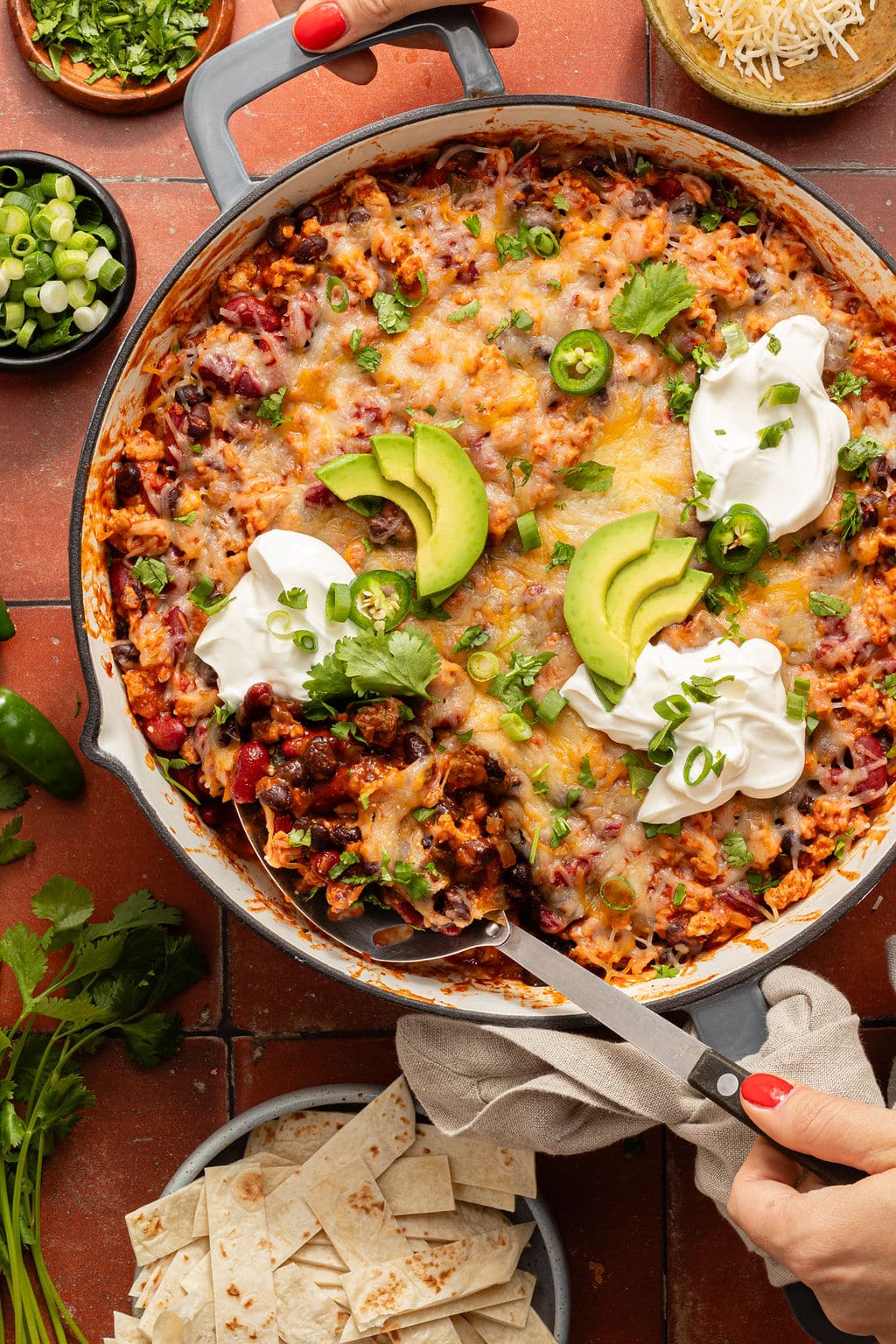 Overhead view of the taco skillet with a serving spoon scooping out a portion, showing melted cheese and hearty filling underneath.