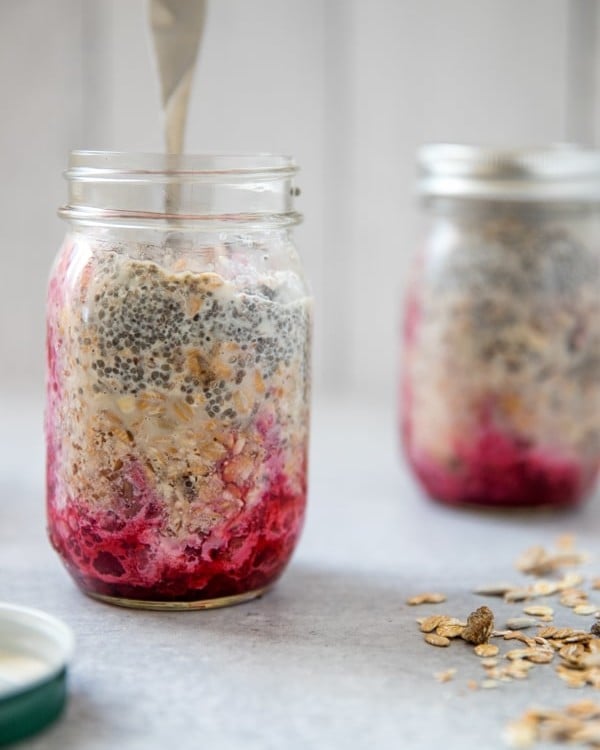 prepping overnight muesli in a mason jar with the fruit on the bottom