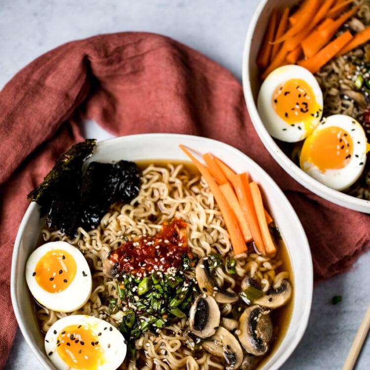 ramen noodles in a bowl with soft boiled eggs, carrots, mushrooms, and broth