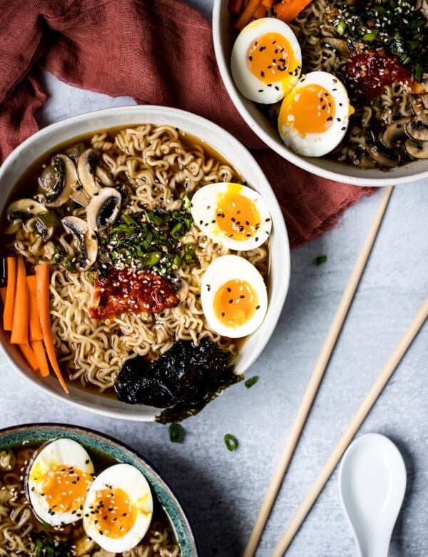 ramen noodles in a bowl with soft boiled eggs, carrots, mushrooms, and broth