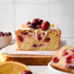 quick bread on a cutting board topped with cranberries