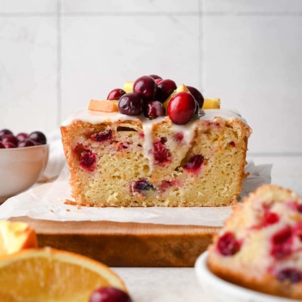 quick bread on a cutting board topped with cranberries
