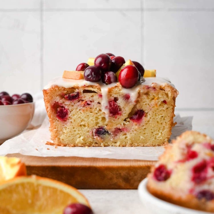 quick bread on a cutting board topped with cranberries