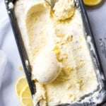 lemon ice cream in a container being scooped with an ice cream scooper