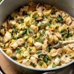 pasta with chicken, mushrooms, and green herbs in a dutch oven pan