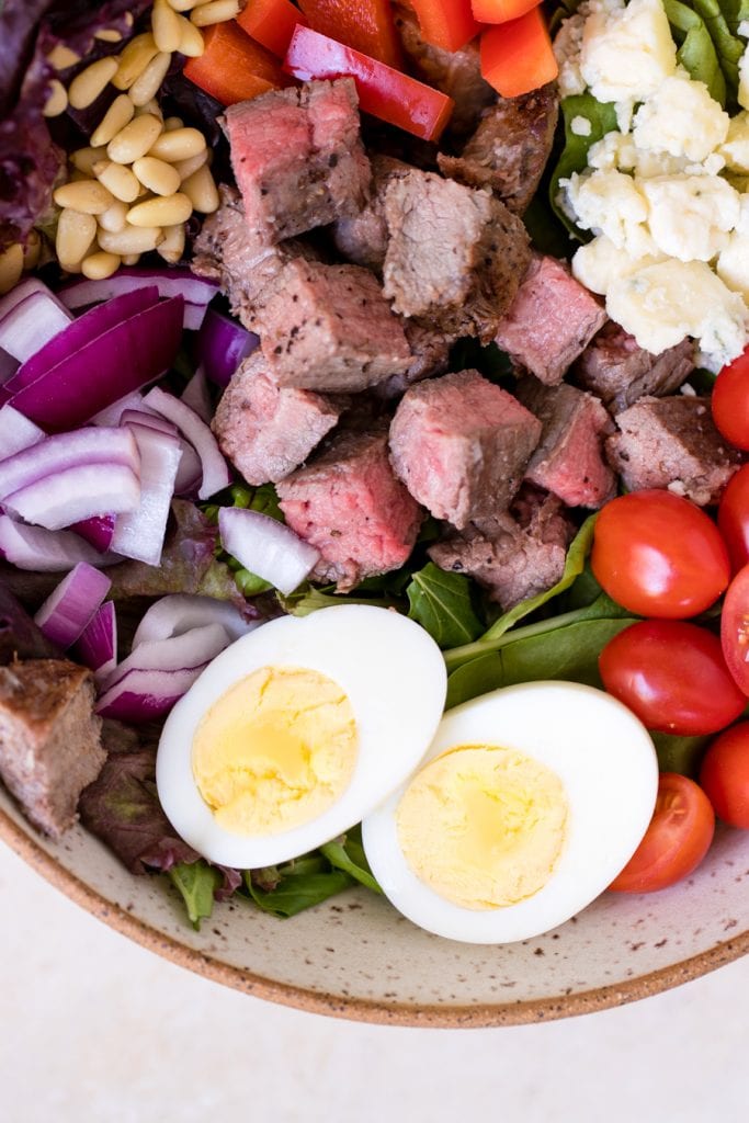 meal prep keto steak cobb salad with avocado dressing poured on top