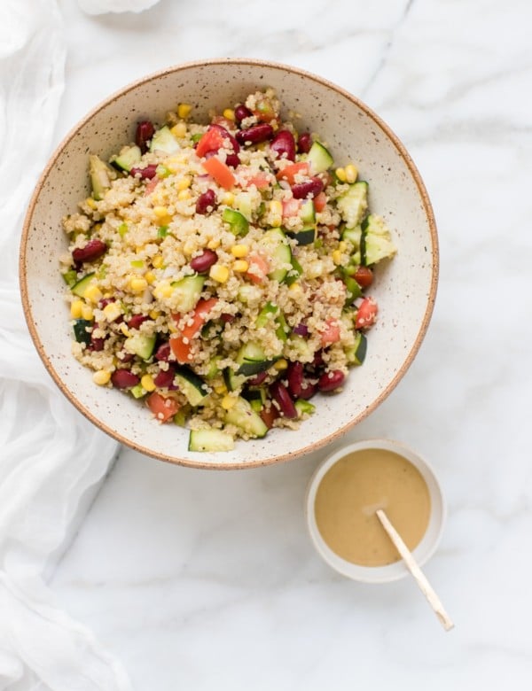 quinoa in a bowl with fresh veggies and a tahini lemon dressing