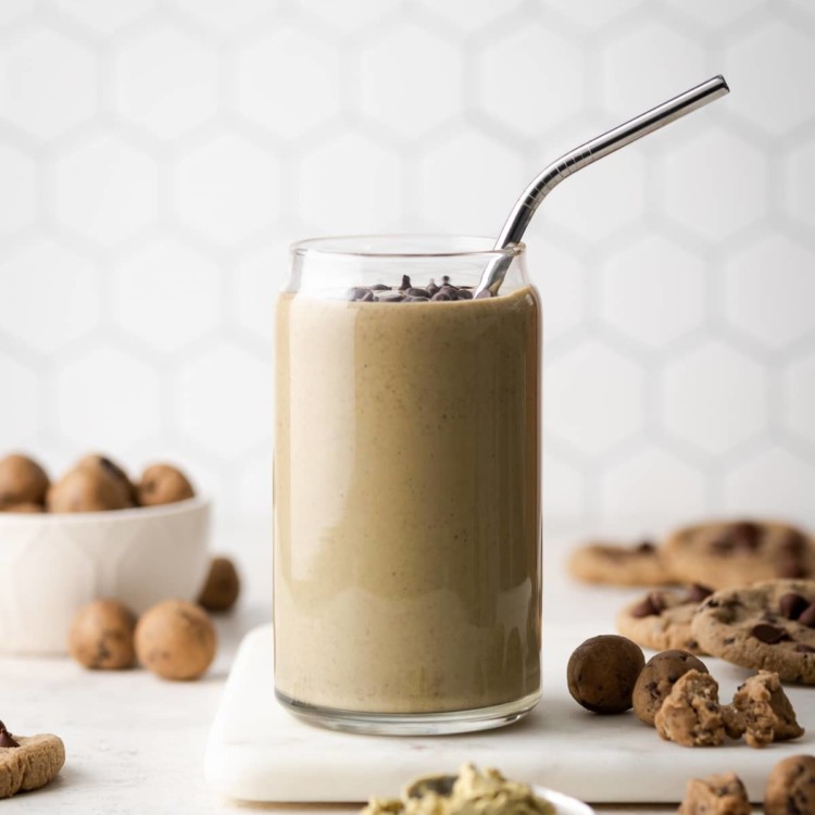 smoothie in a glass on a marble board with a metal straw in it and chocolate chips on top