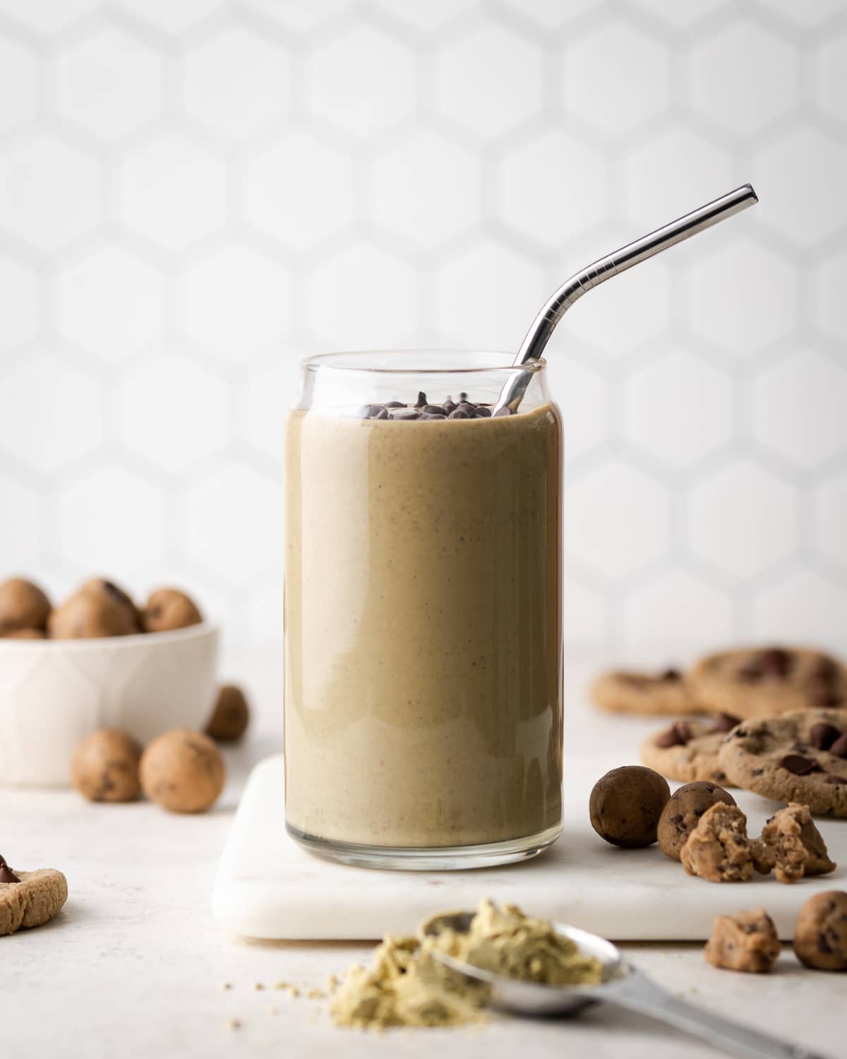 smoothie in a glass on a marble board with a metal straw in it and chocolate chips on top