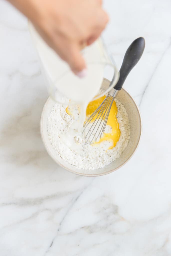 milk being poured into dry ingredients