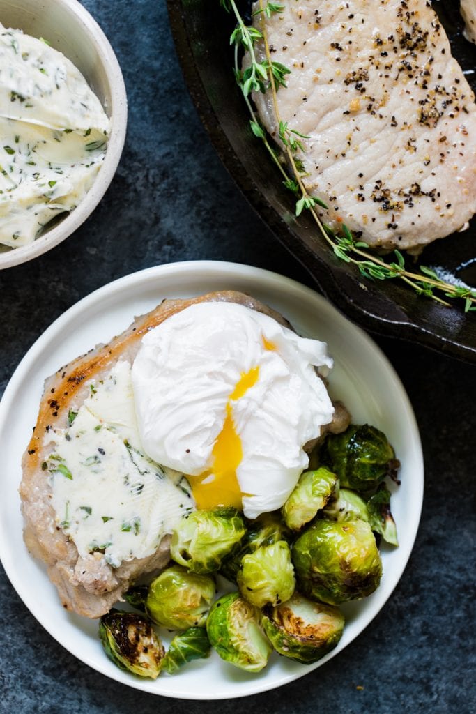 pork chops and eggs on a white plate
