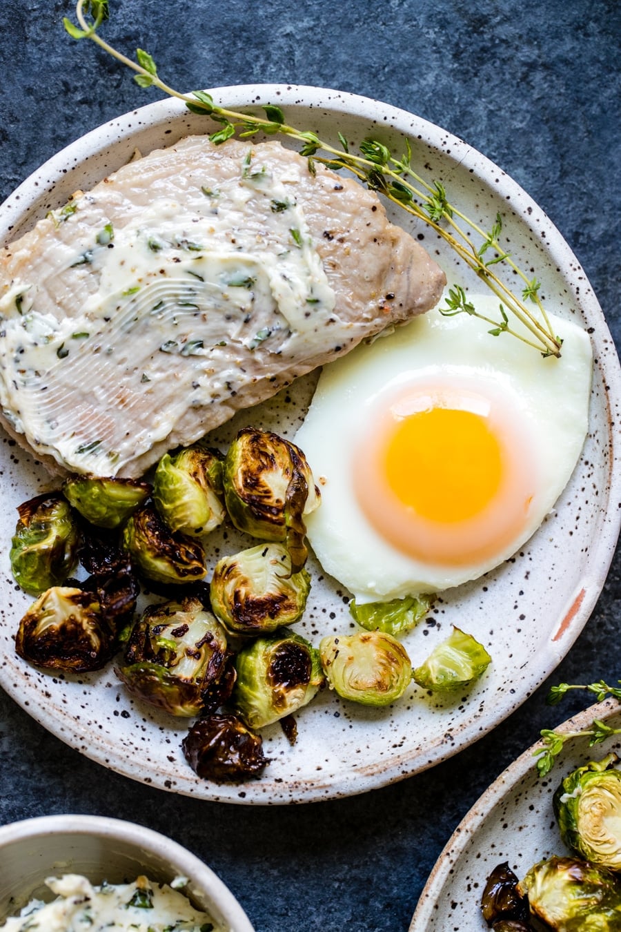 pork chops, eggs and Brussels sprouts on a white plate