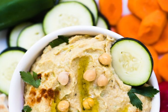 hummus in a white bowl topped with olive oil and parsley
