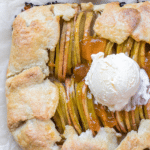 a baked apple galette on parchment paper with apricot jam