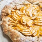 a baked apple galette on parchment paper with apricot jam