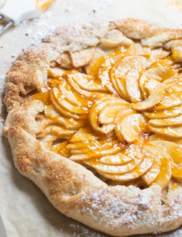 a baked apple galette on parchment paper with apricot jam