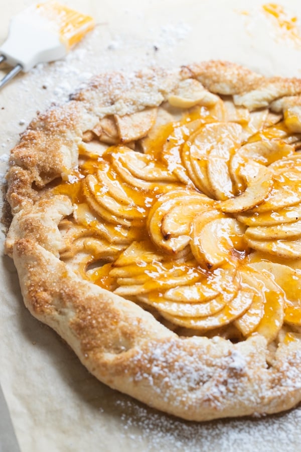 a baked apple galette on parchment paper with apricot jam