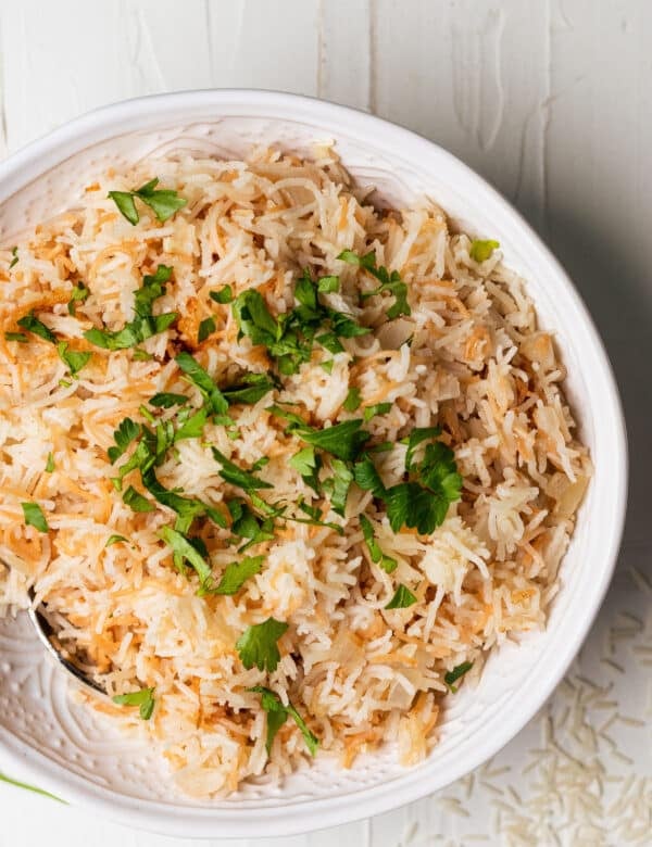 rice pilaf in a white bowl topped with fresh parsley