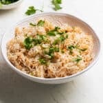 rice pilaf in a white bowl topped with fresh parsley