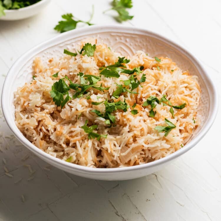 rice pilaf in a white bowl topped with fresh parsley