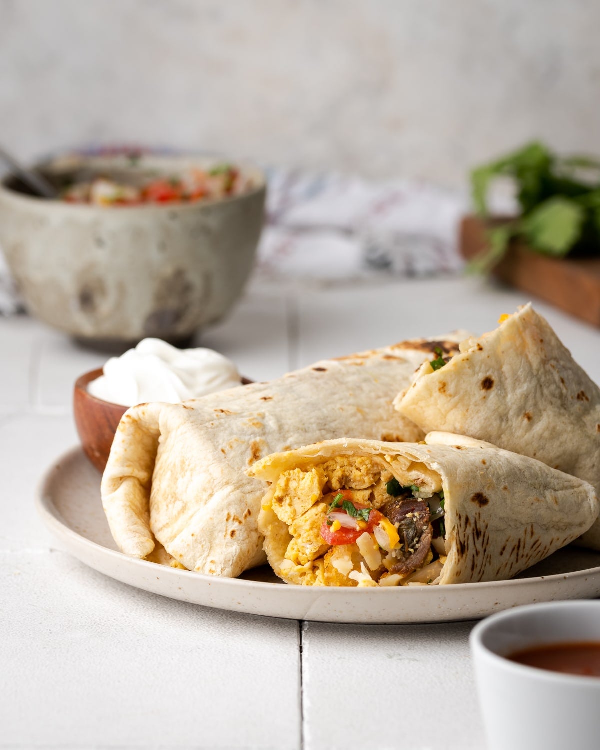 breakfast burritos on a white plate cut in half