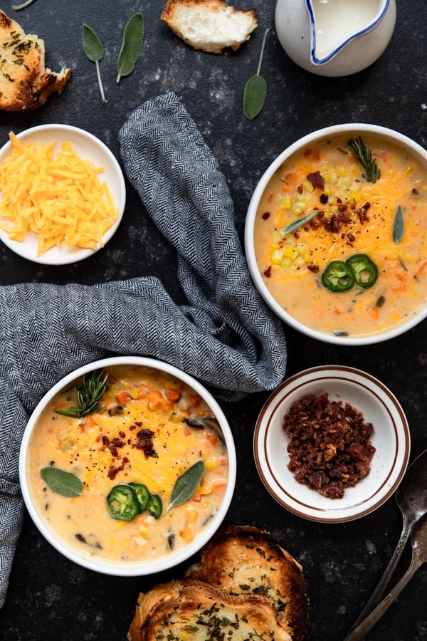 corn chowder in a white bowl topped with cheese and herbs