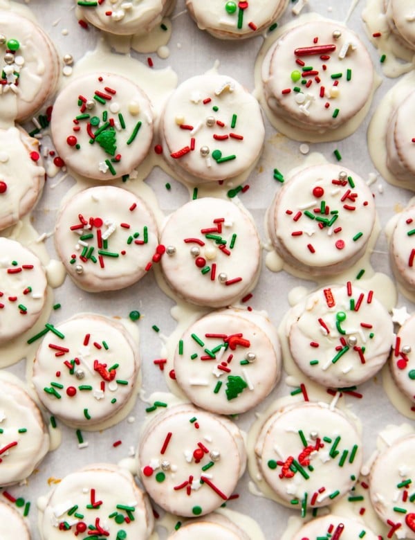 ritz cracker cookies with white icing and christmas sprinkles on a sheet
