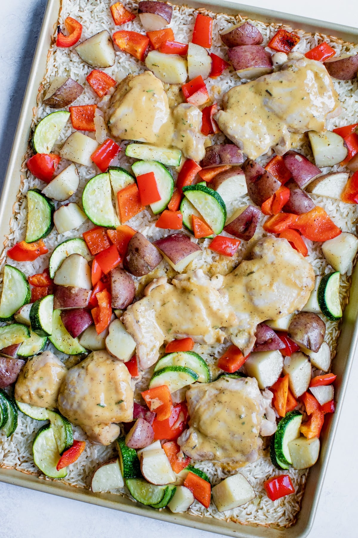 chicken rice and veggies on a gold baking sheet