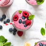 a berry smoothie in a glass topped with fresh berries
