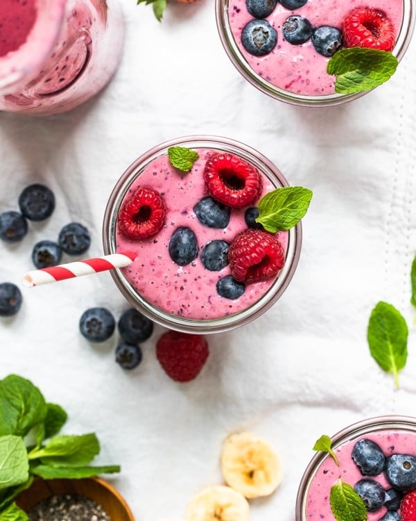 a berry smoothie in a glass topped with fresh berries