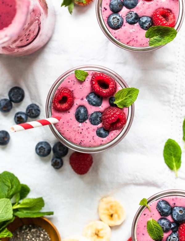 a berry smoothie in a glass topped with fresh berries