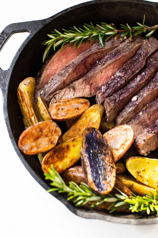 baked flank steak and fingerling potatoes in a cast iron skillet