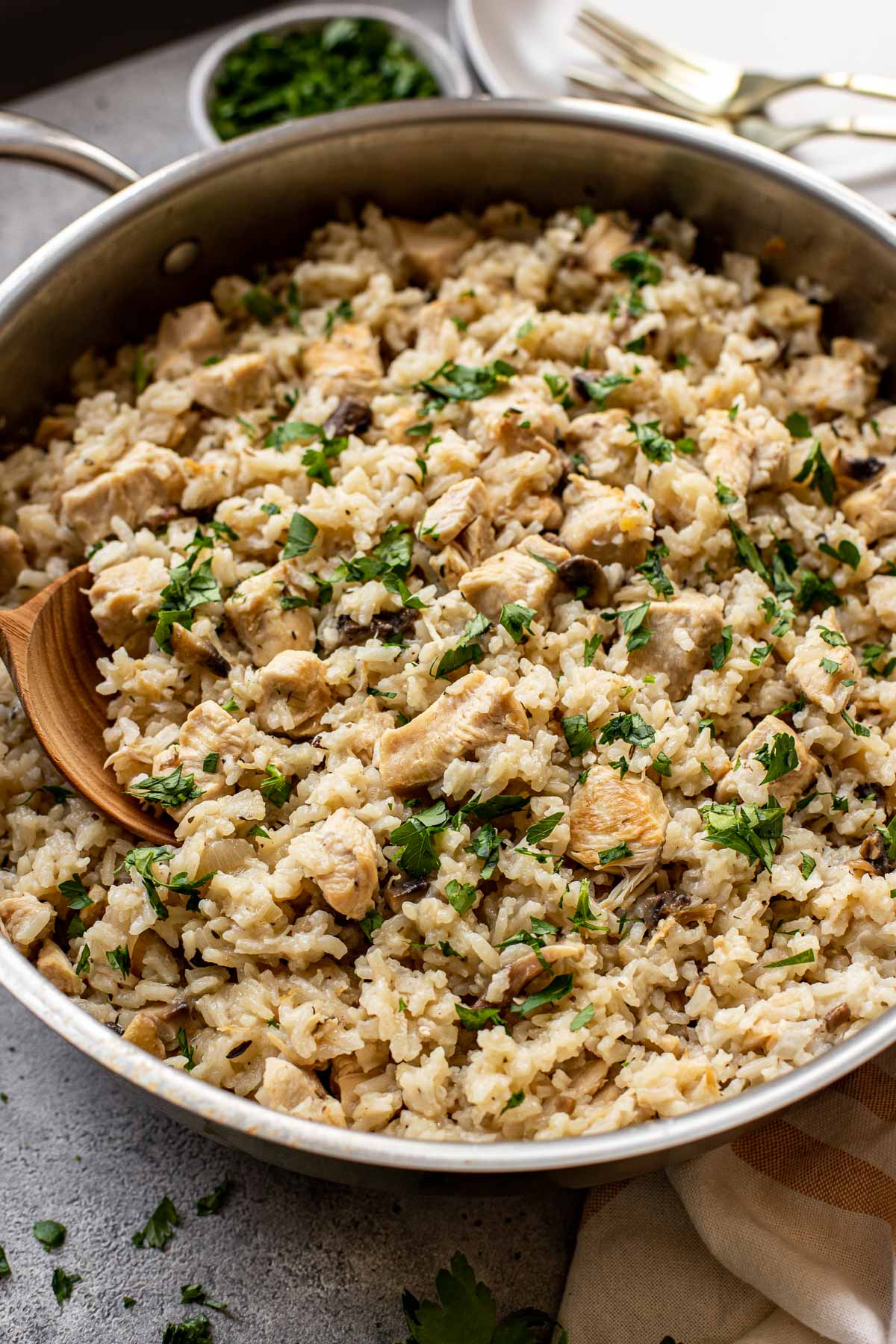 Chicken, rice and mushrooms in a skillet garnished with parsley. 