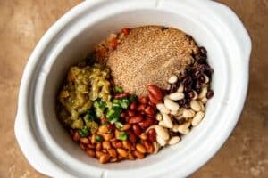 beans and chili seasonings in a white slow cooker.