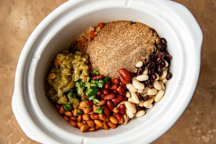 beans and chili seasonings in a white slow cooker.