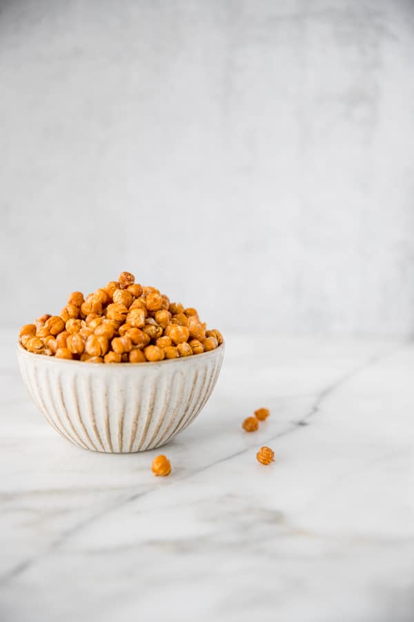 a bowl of roasted chickpeas on a marble table